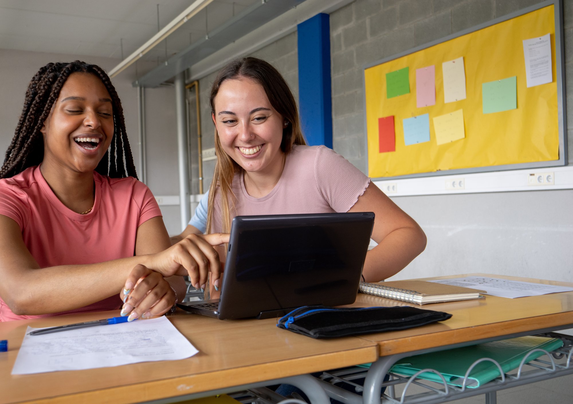 Two female students learning using a laptop in a school